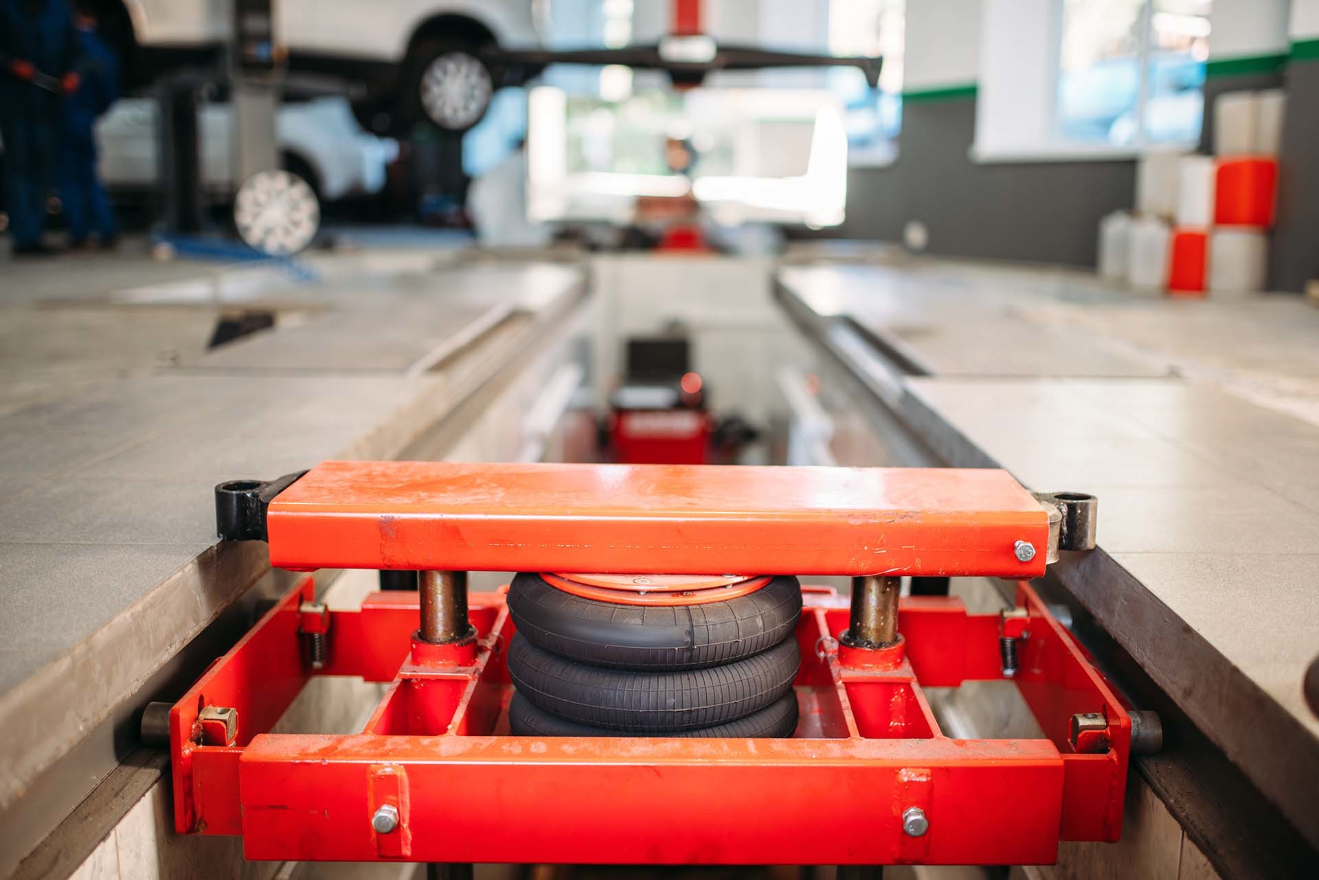 Rotes Hebezeug mit Luftfedern in einer Werkstatt, repräsentiert die sichere und zuverlässige Hubtechnik von AH Werkstatt Service für Werkstattausrüstung.