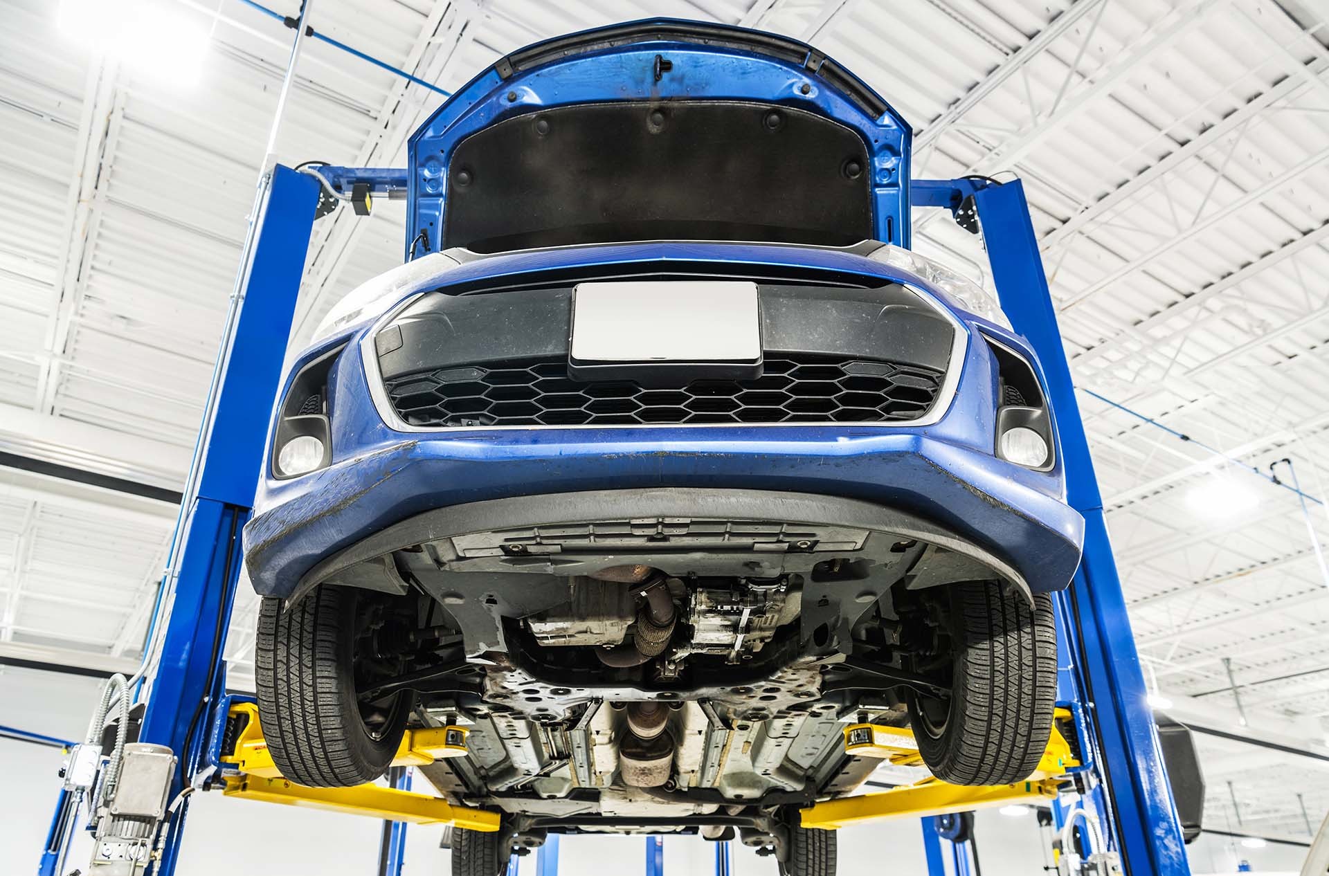 Blaues Auto auf einer Hebebühne in einer Werkstatt – Hebebühnen und Werkstattausrüstung von AH Werkstatt Service, Anbieter von sicheren Hublösungen für Werkstätten.