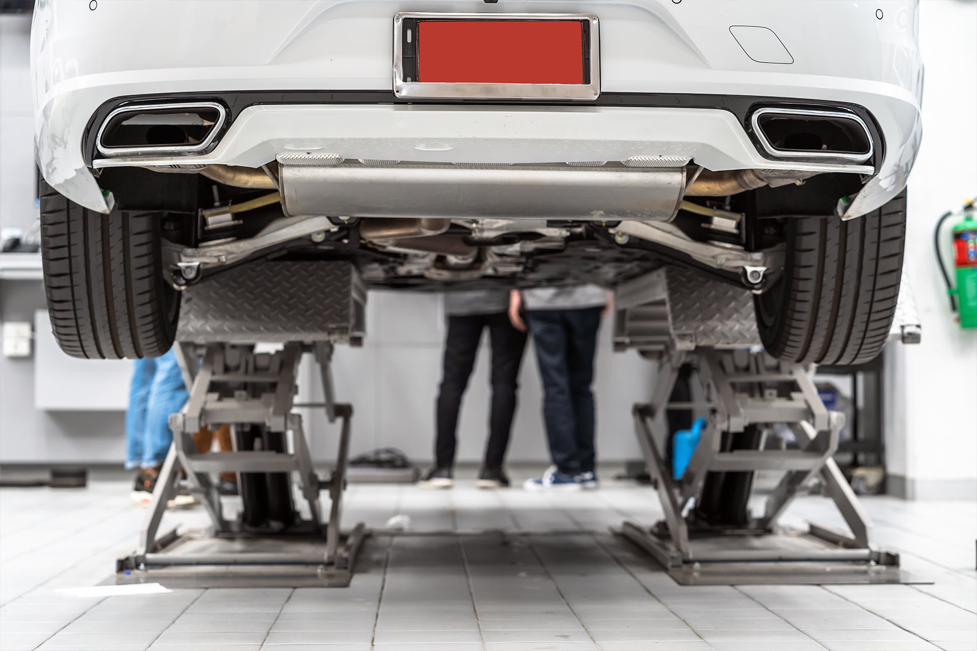 Weißes Auto auf einer hydraulischen Hebebühne in einer Werkstatt – zeigt die zuverlässige Hubtechnik und Werkstattausrüstung von AH Werkstatt Service.