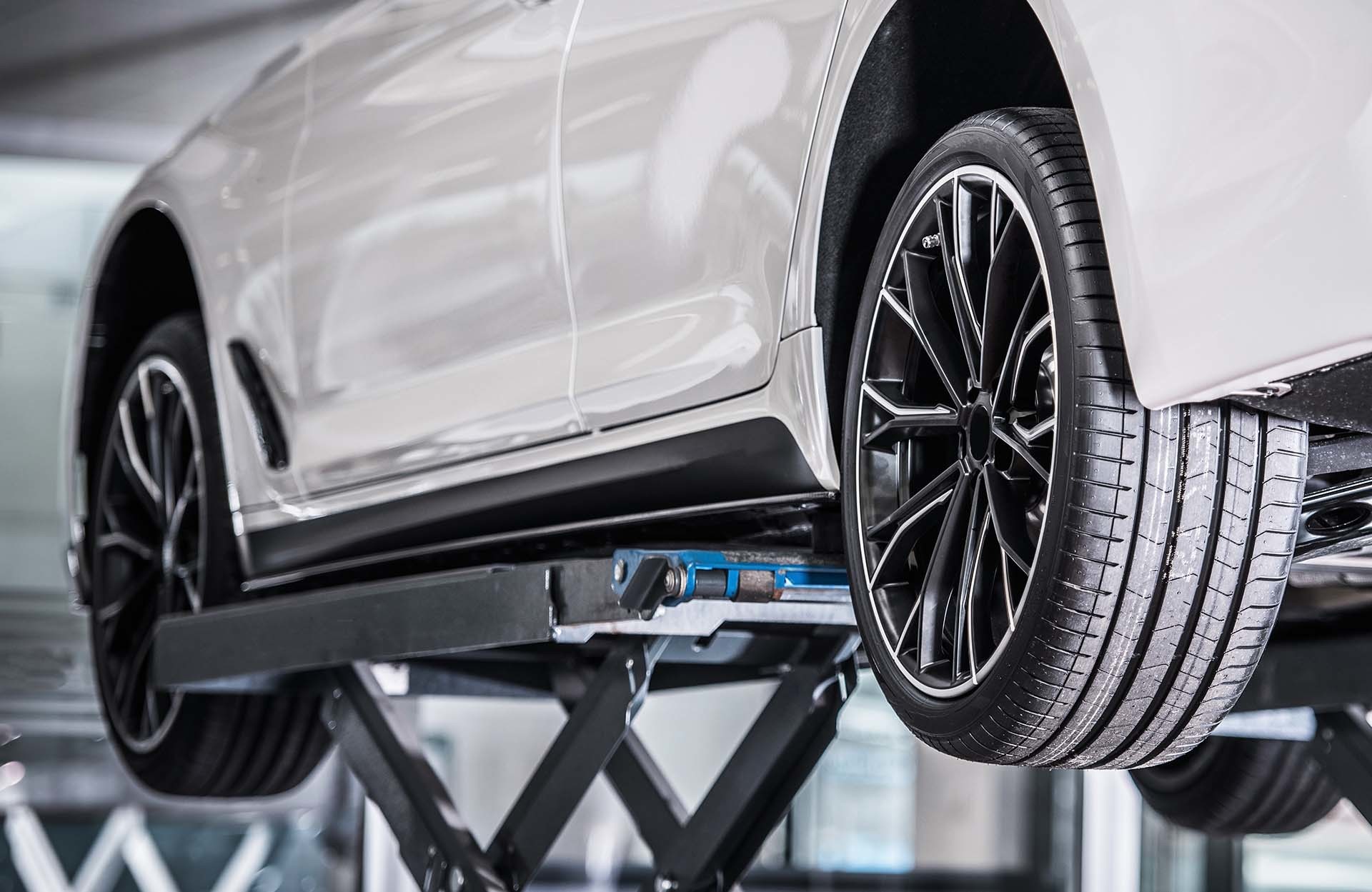 Weißes Auto auf einer professionellen Werkstatt-Hebebühne, repräsentativ für die sichere und zuverlässige Hebetechnik von AH Werkstatt Service, dem Spezialisten für Werkstattausrüstung und Hebebühnen.
